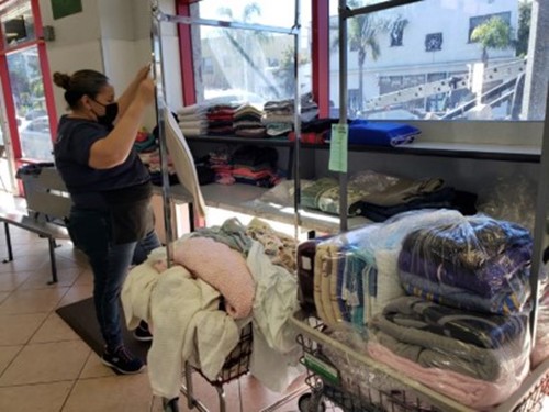 Laundry attendant folding laundry in a cart